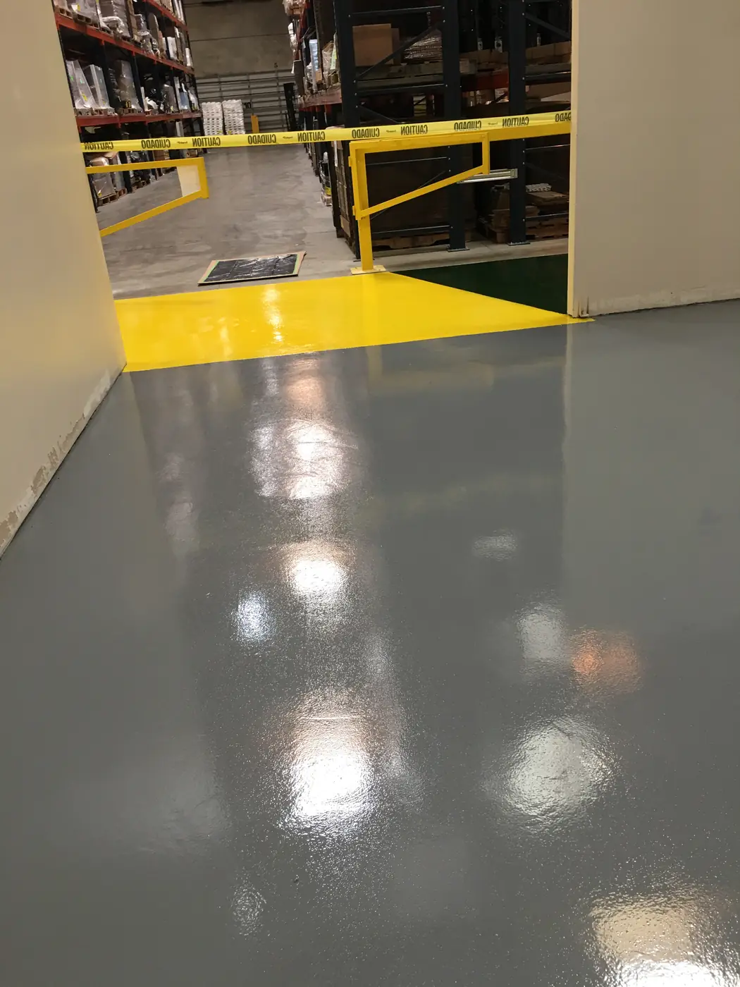 Gray epoxy floor with a yellow bordered walkway leading into a warehouse