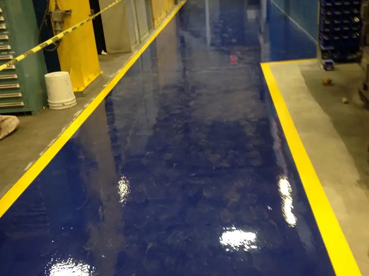 Royal blue epoxy plant floor edged with yellow safety striping