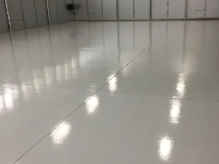 White gloss epoxy floor reflecting daylight in a warehouse