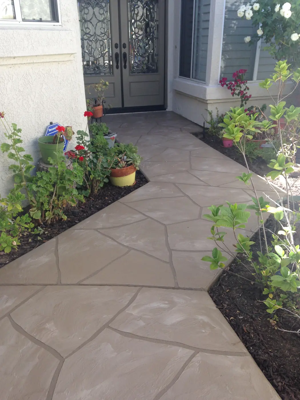 Flagstone-pattern overlay on an entry patio with planted borders
