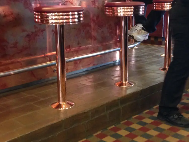 Copper bar stools on a checcurboard patterned decorative floor overlay