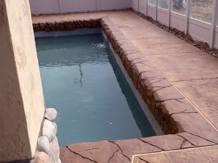 Stamped overlay deck around a rectangular spa with a tiled edge
