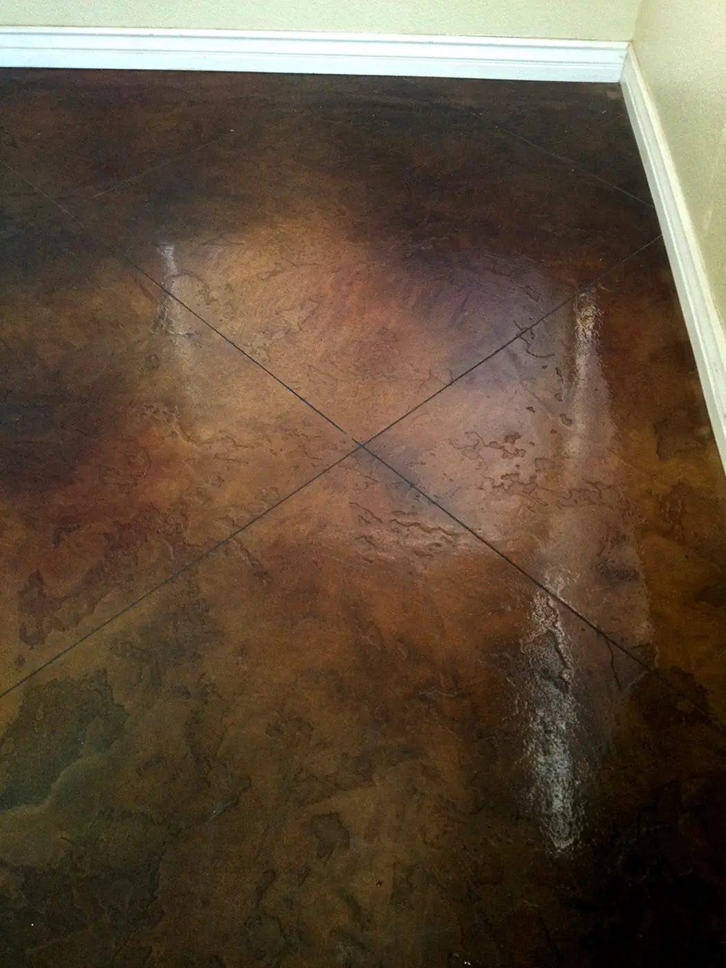 Dark brown stained concrete floor scored in a diamond pattern