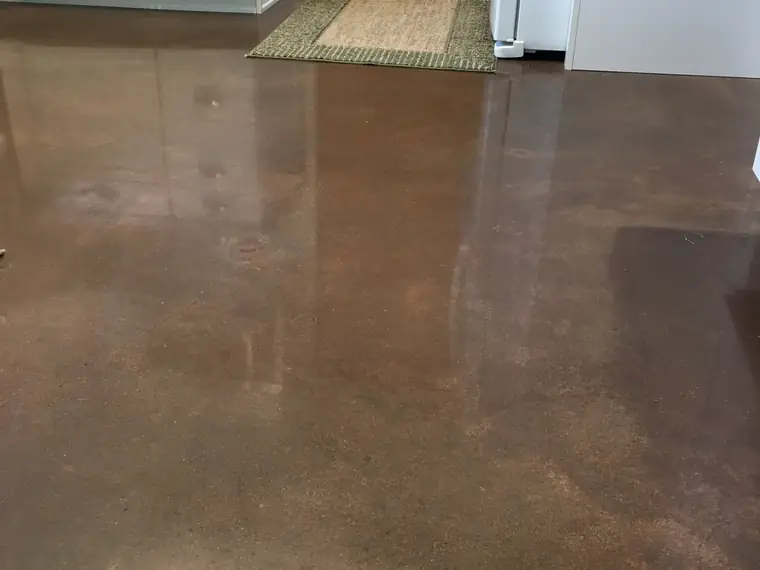 Brown polished concrete kitchen floor with rugs and appliances