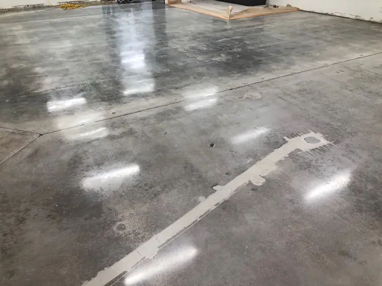 Polished gray concrete floor reflecting overhead lighting