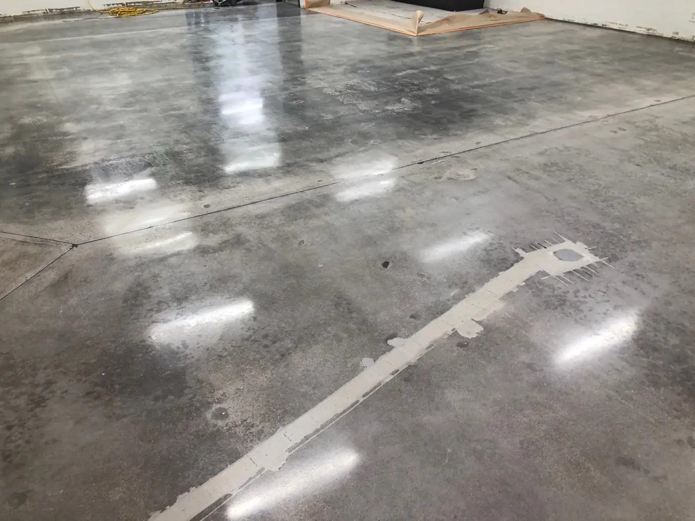 Polished gray concrete floor reflecting overhead lighting