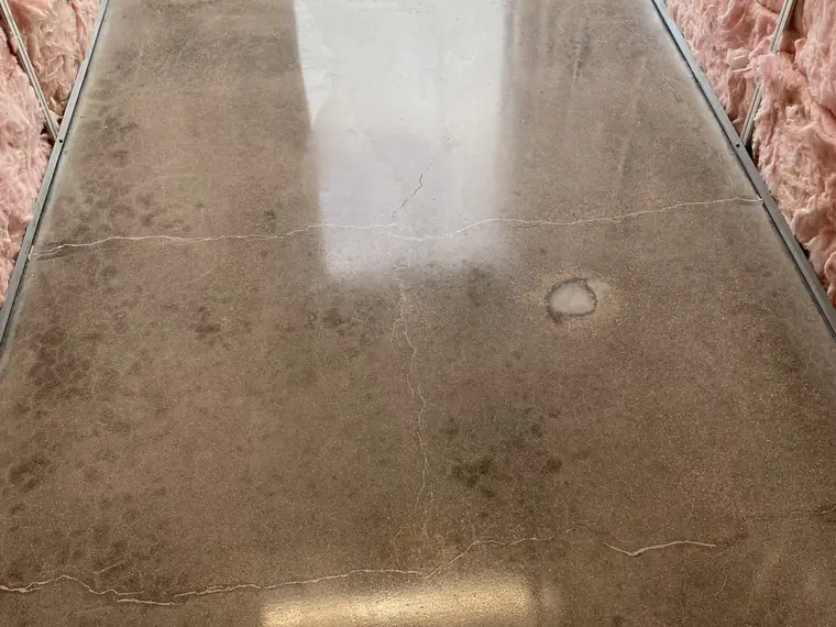Polished concrete floor in a room still lined with insulation batts