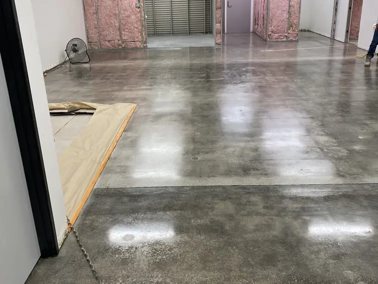 Polished concrete floor in a building under construction with framed walls