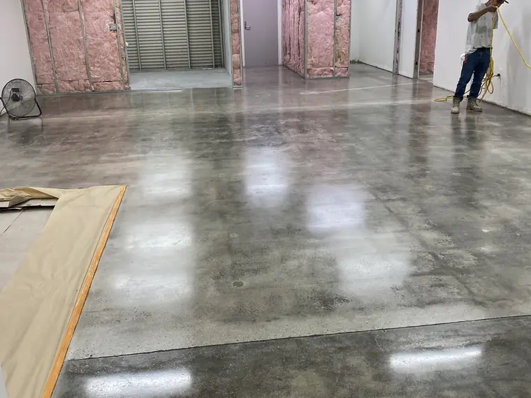 Worker crossing a freshly polished concrete floor in a partly built room