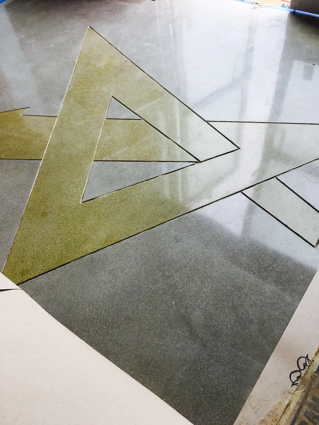 Close view of a gold stained triangle inlay in polished concrete