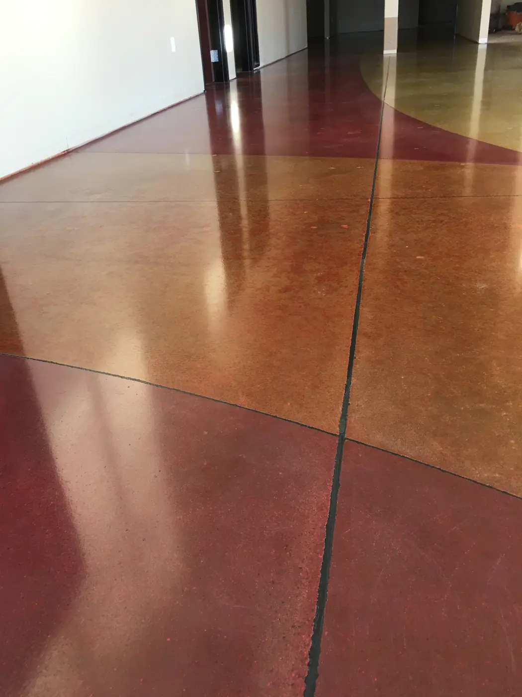 Orange and red stained polished concrete with a sweeping saw-cut curve