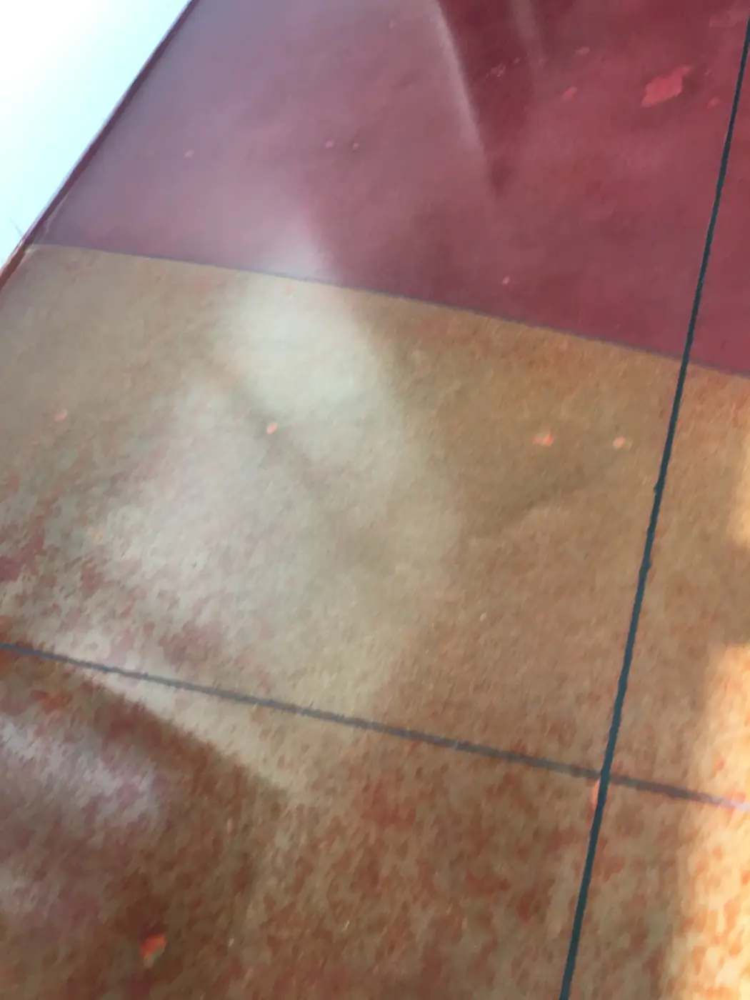 Deep red and orange stained polished concrete with a saw-cut joint