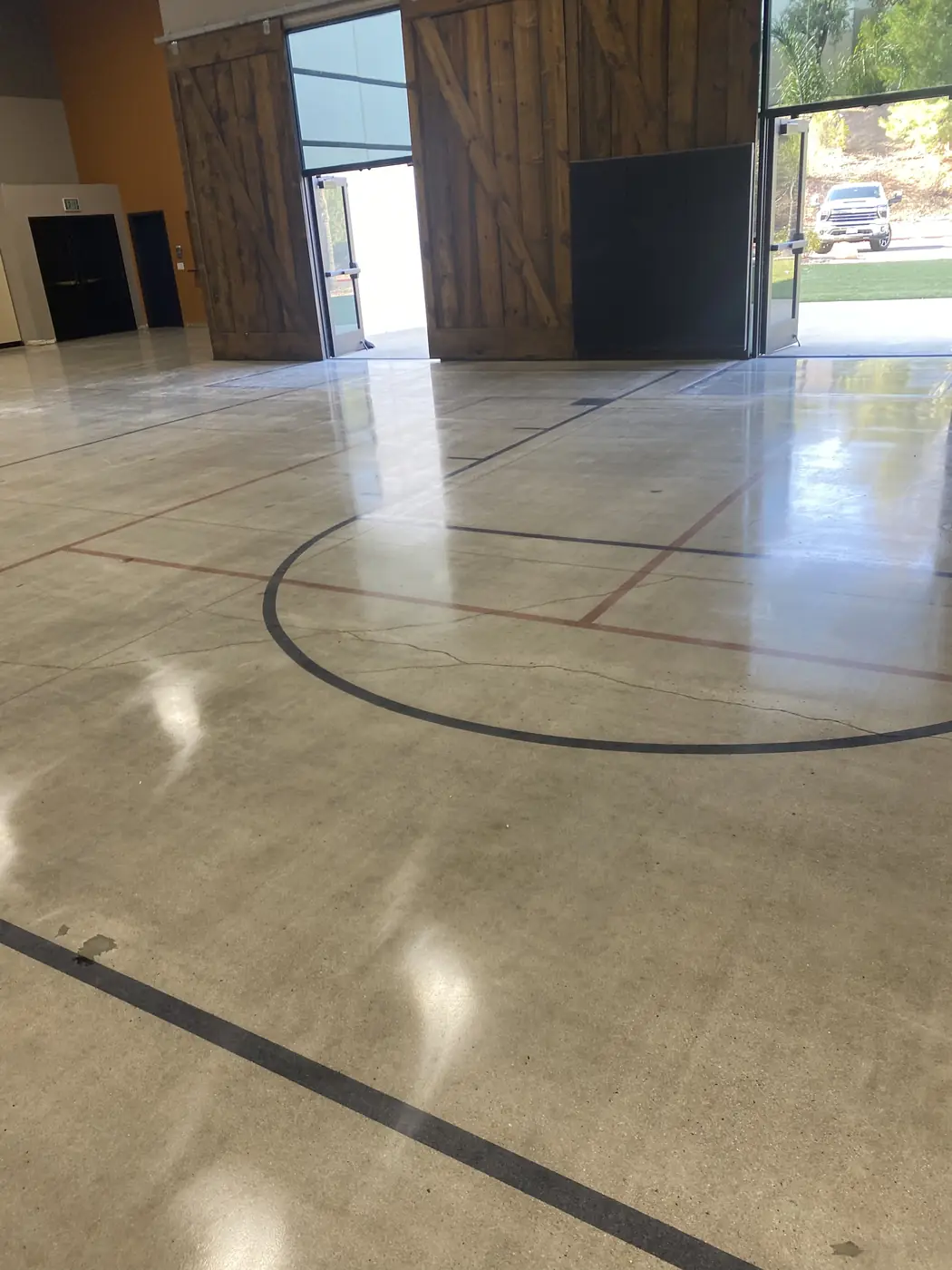 Polished concrete gym floor with a saw-cut circle and red court lines