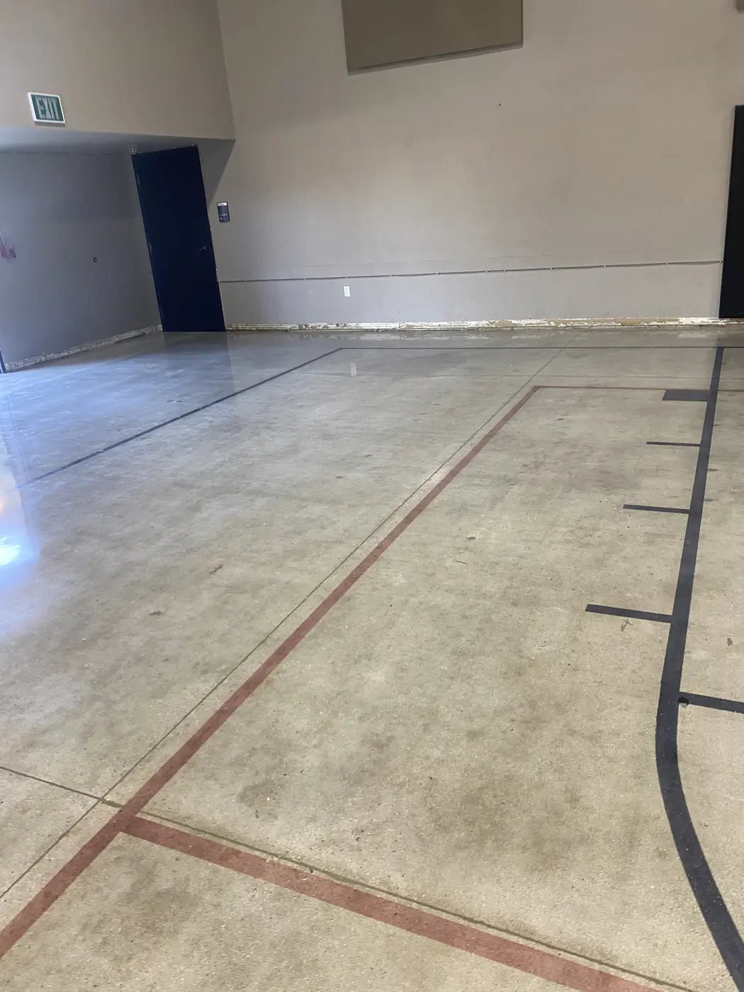 Saw-cut red and black court markings across a polished concrete floor