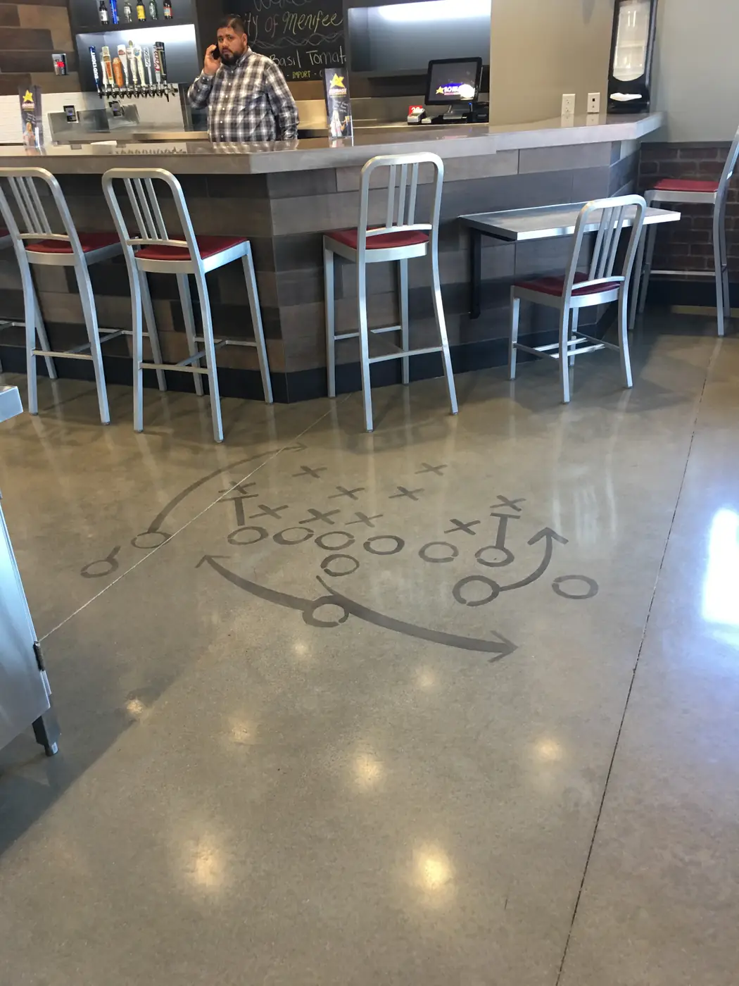 Football play diagram cut into a polished concrete floor beside a servery counter