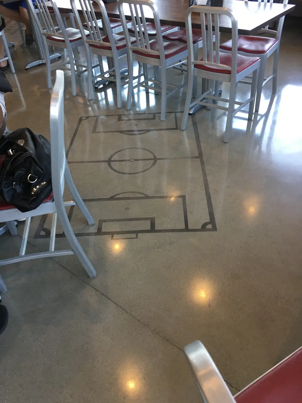 Saw-cut pitch diagram in a polished concrete floor under cafe seating