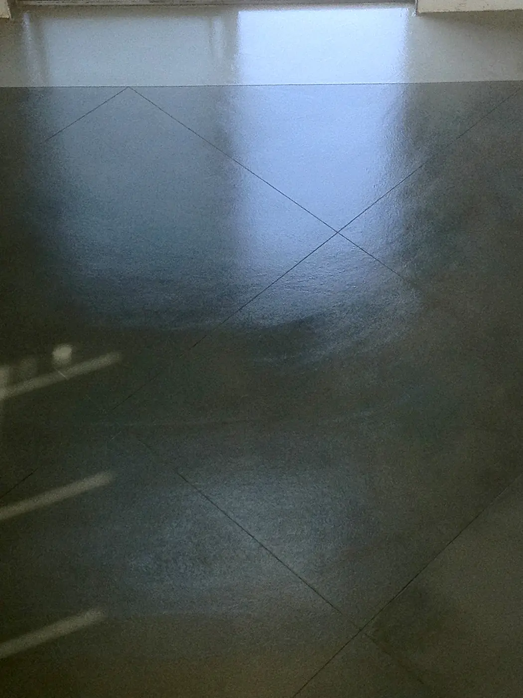 Dark green-gray polished concrete floor with a saw-cut joint