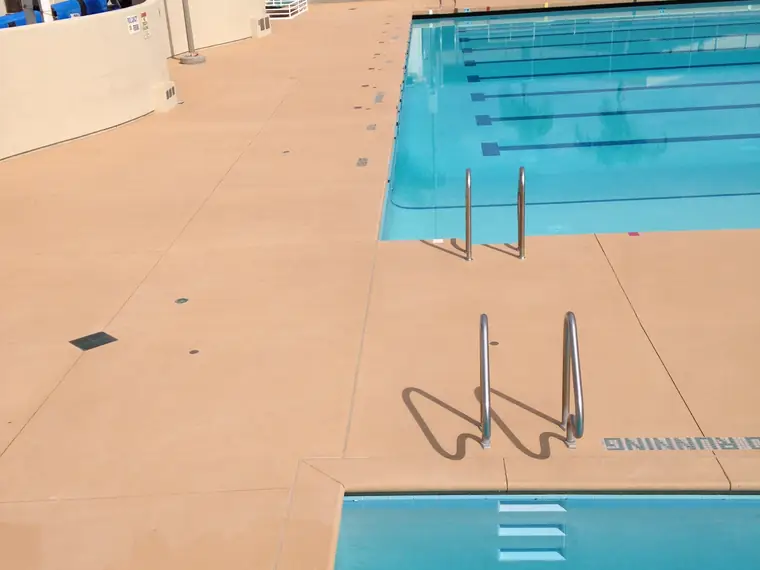 Tan pool deck around a competition lap pool with lane markings in the water