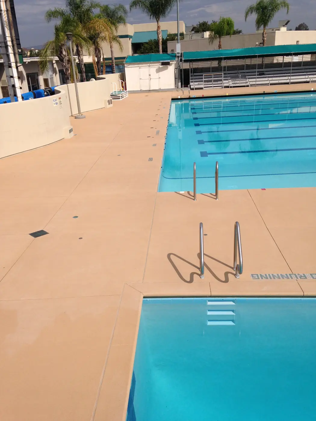 Tan pool deck around a competition lap pool with lane markings in the water