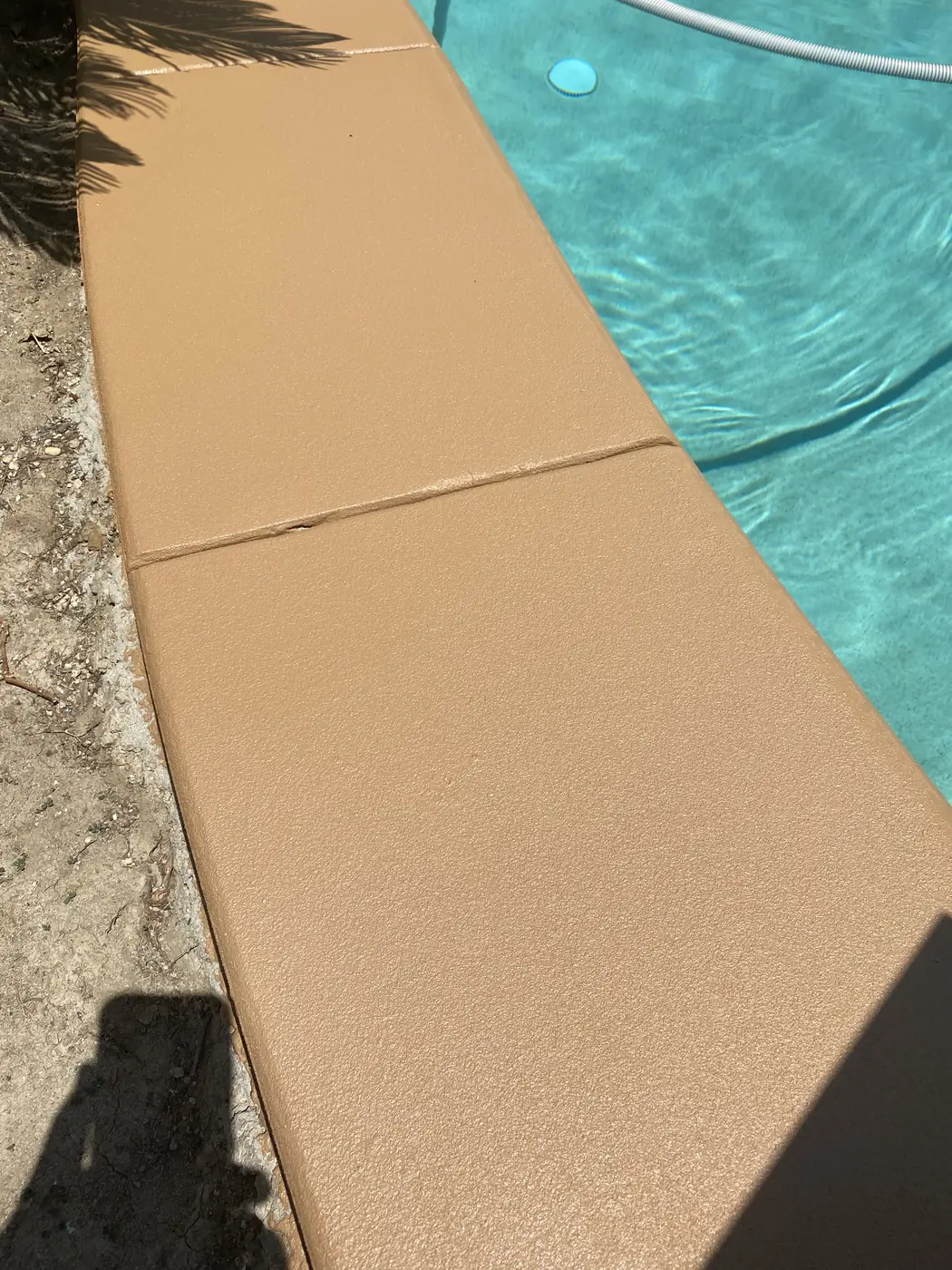 Textured tan coping meeting turquoise pool water