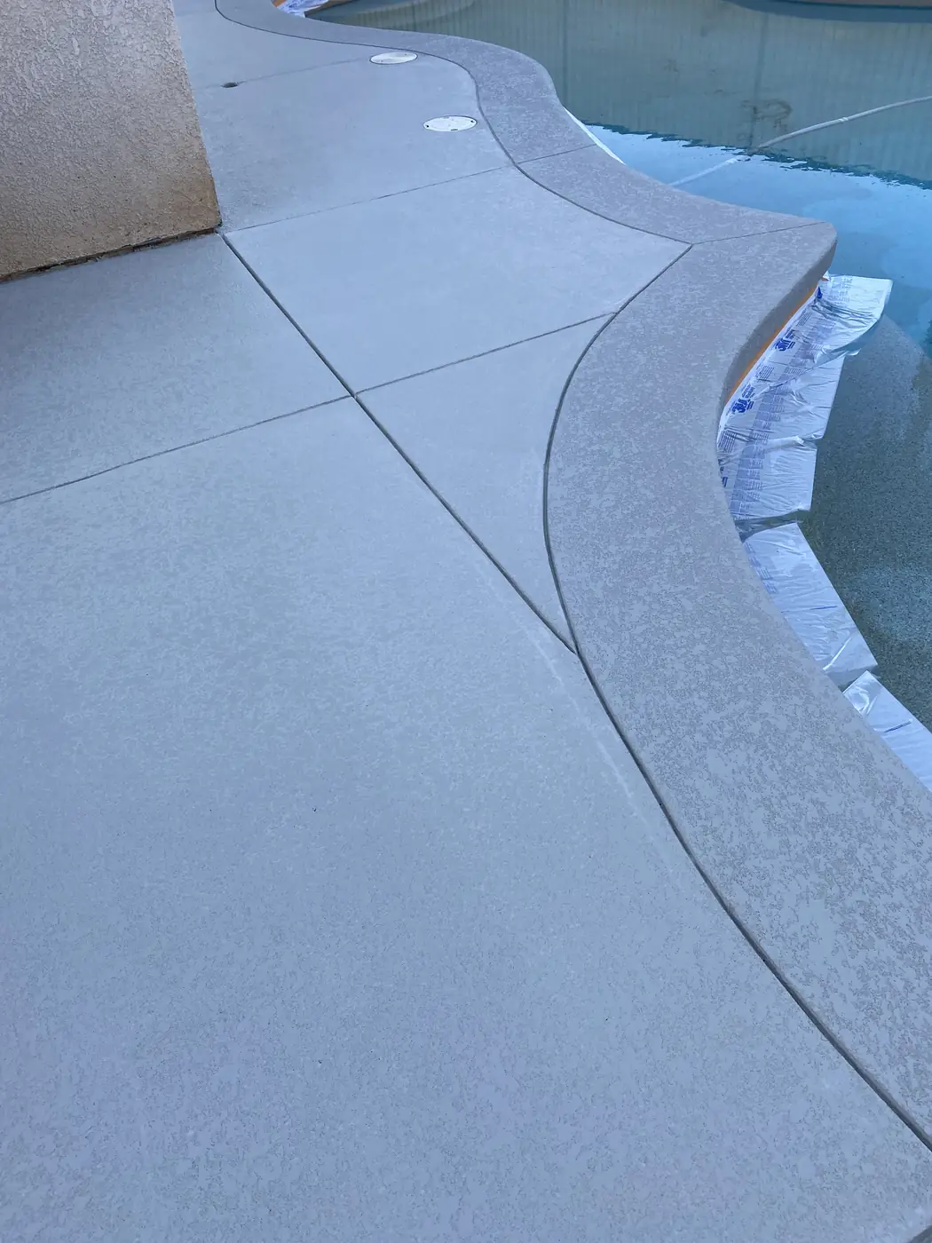 Blue-gray textured deck curving around the edge of a pool