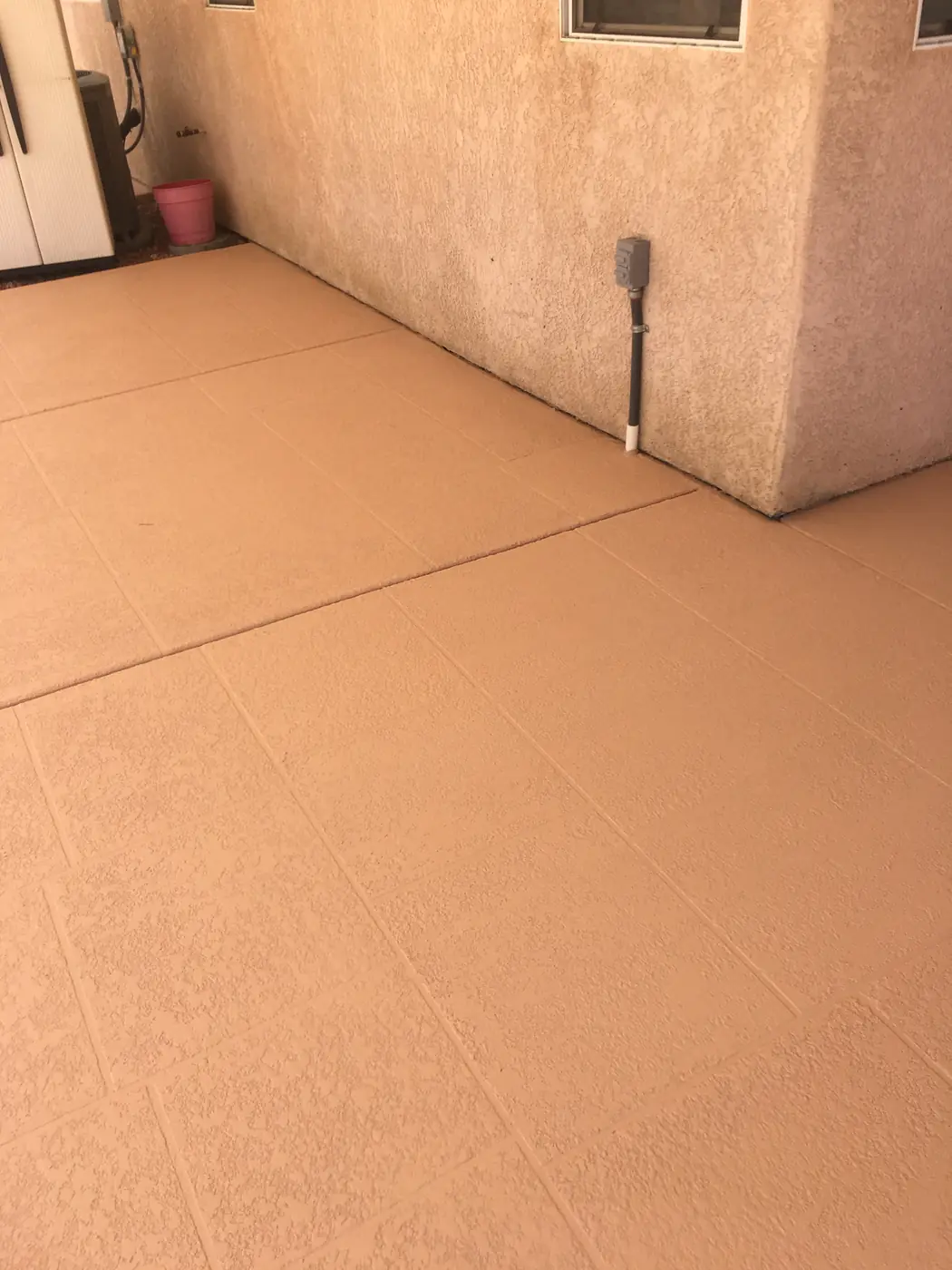 Terracotta textured pool deck meeting a stucco wall
