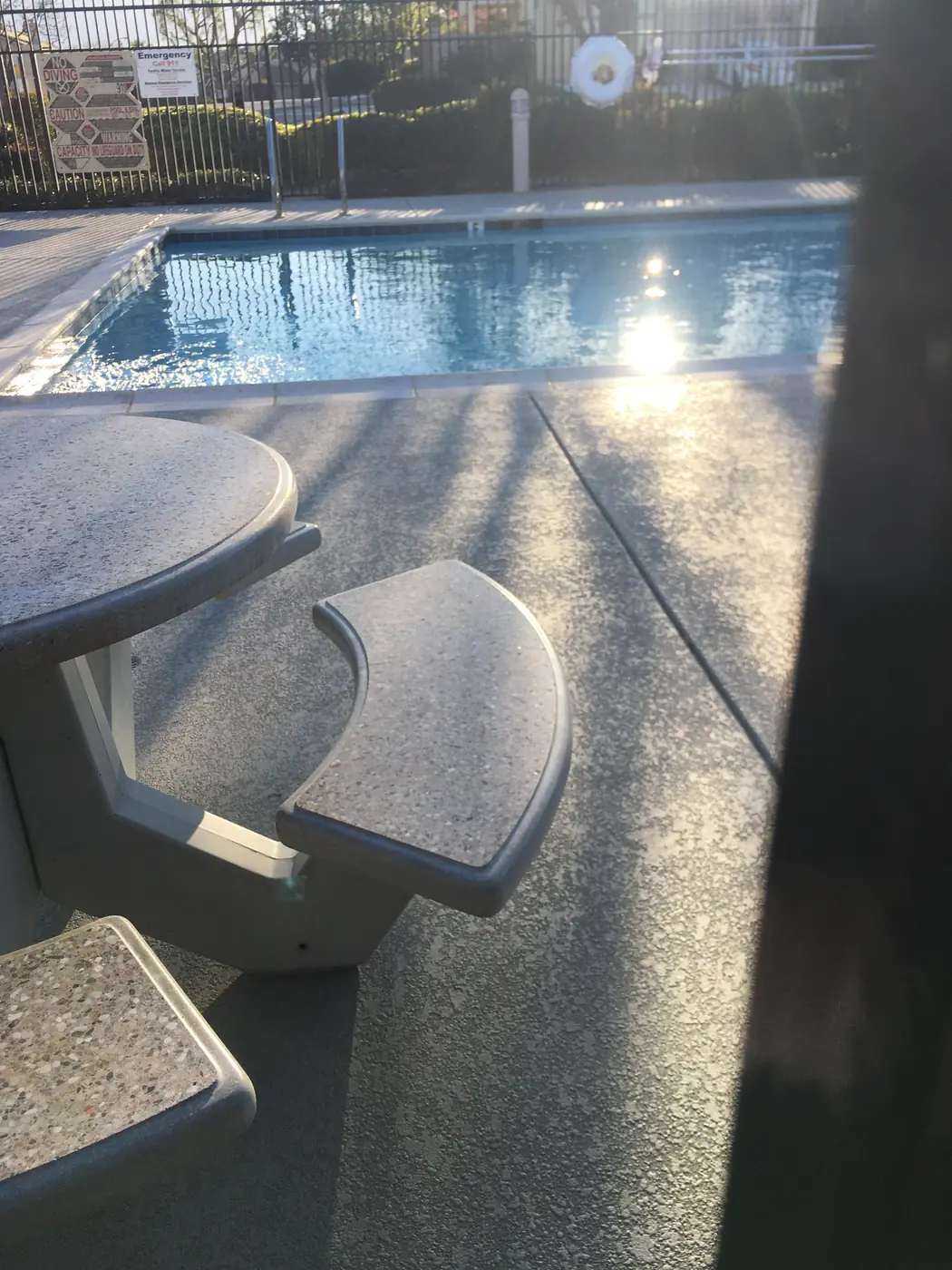 Concrete table and benches on a speckled gray pool deck