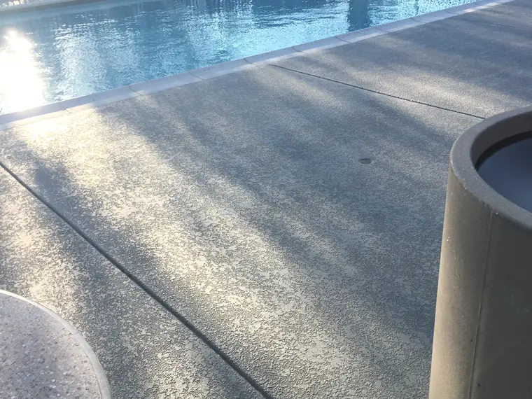 Sunlight raking across a freshly coated gray pool deck