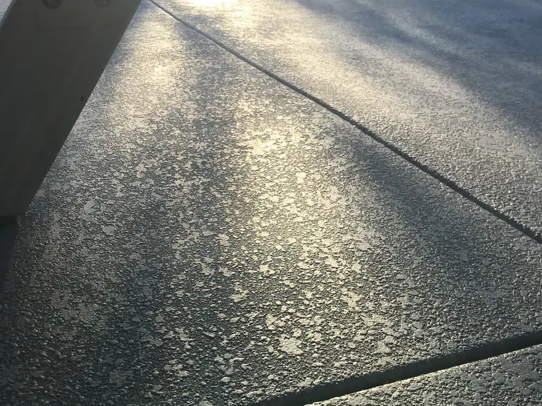 Textured gray deck lit by low sun beside a pool