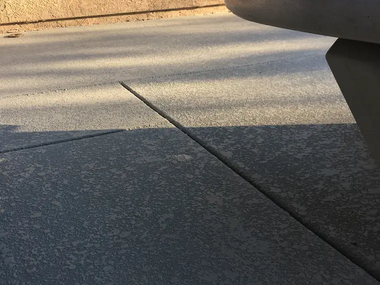 Gray textured pool deck with a concrete table at the edge of frame