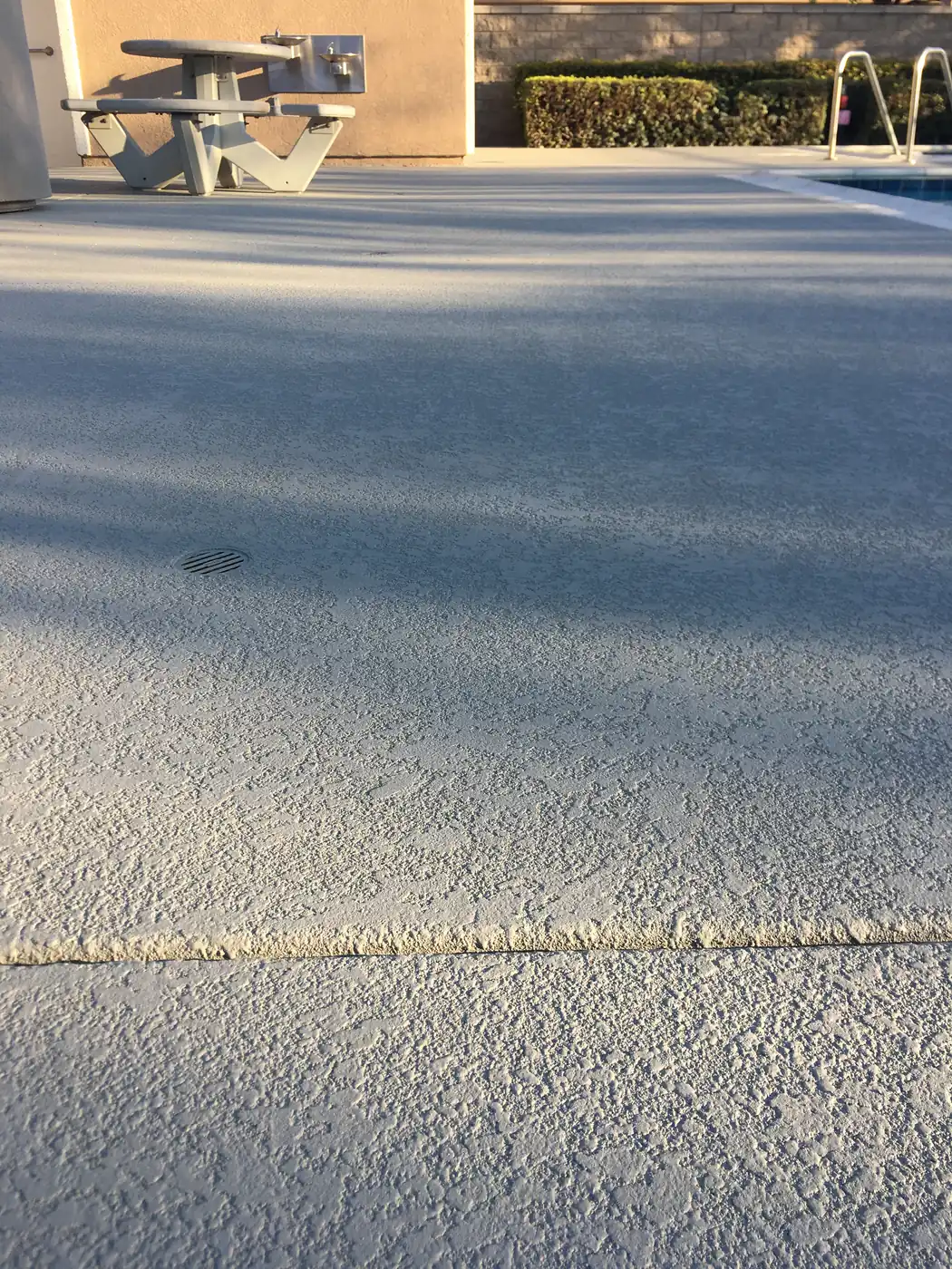 Gray pool deck with a drain set flush into the textured surface