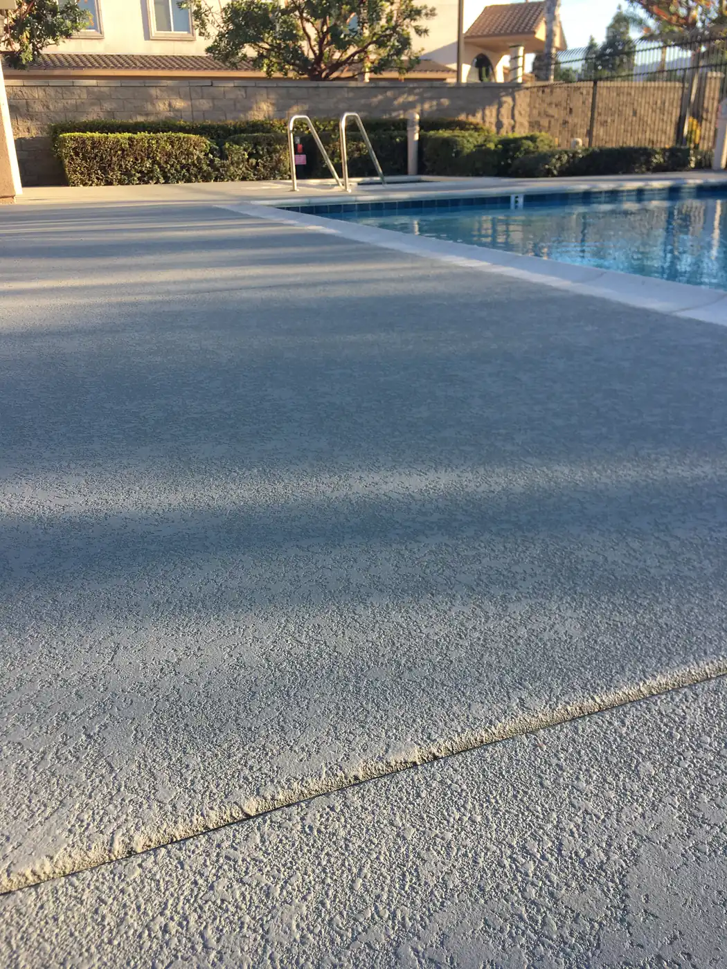 Gray textured deck running alongside a commercial lap pool