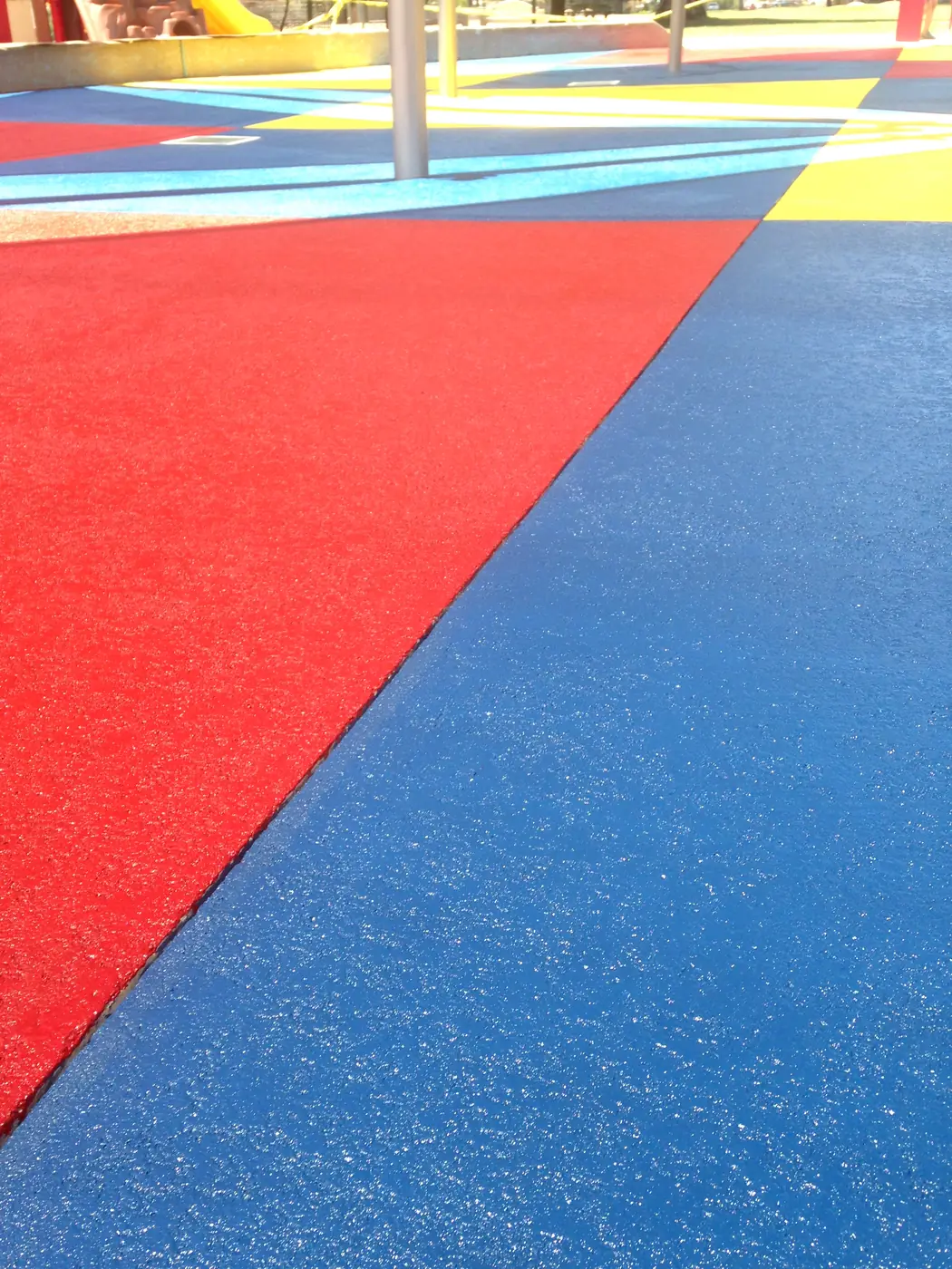 Red, blue and yellow coated panels meeting on a splash pad surface