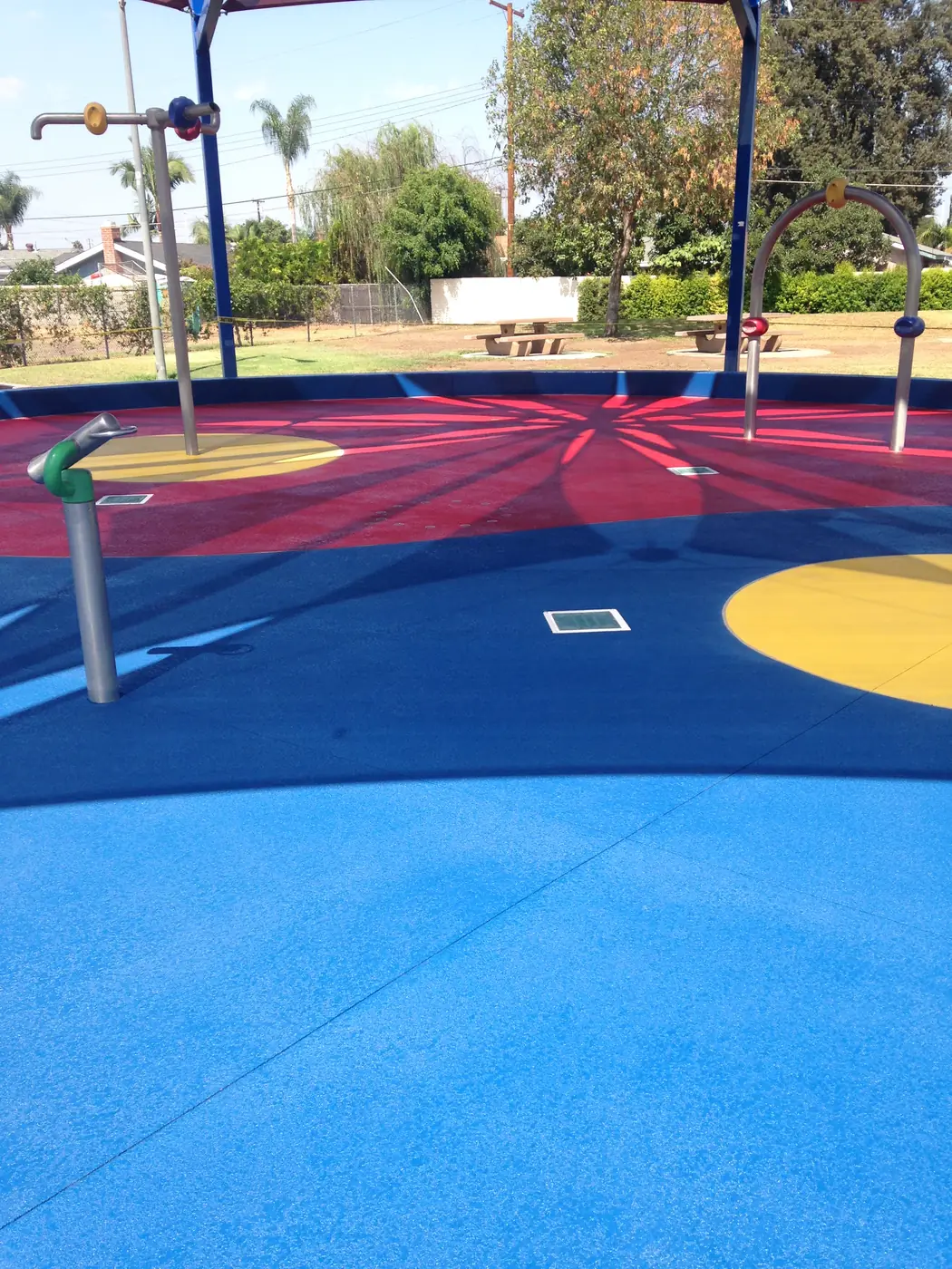 Park splash pad in red, blue and yellow with water play equipment