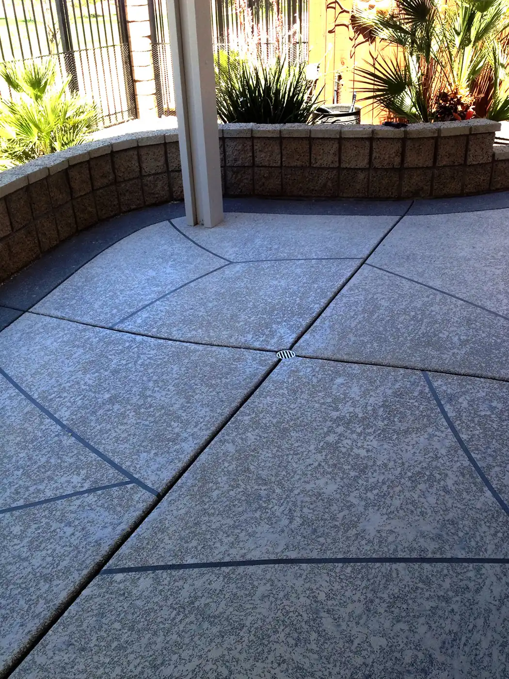 Blue-gray textured patio deck with a brick planter wall behind
