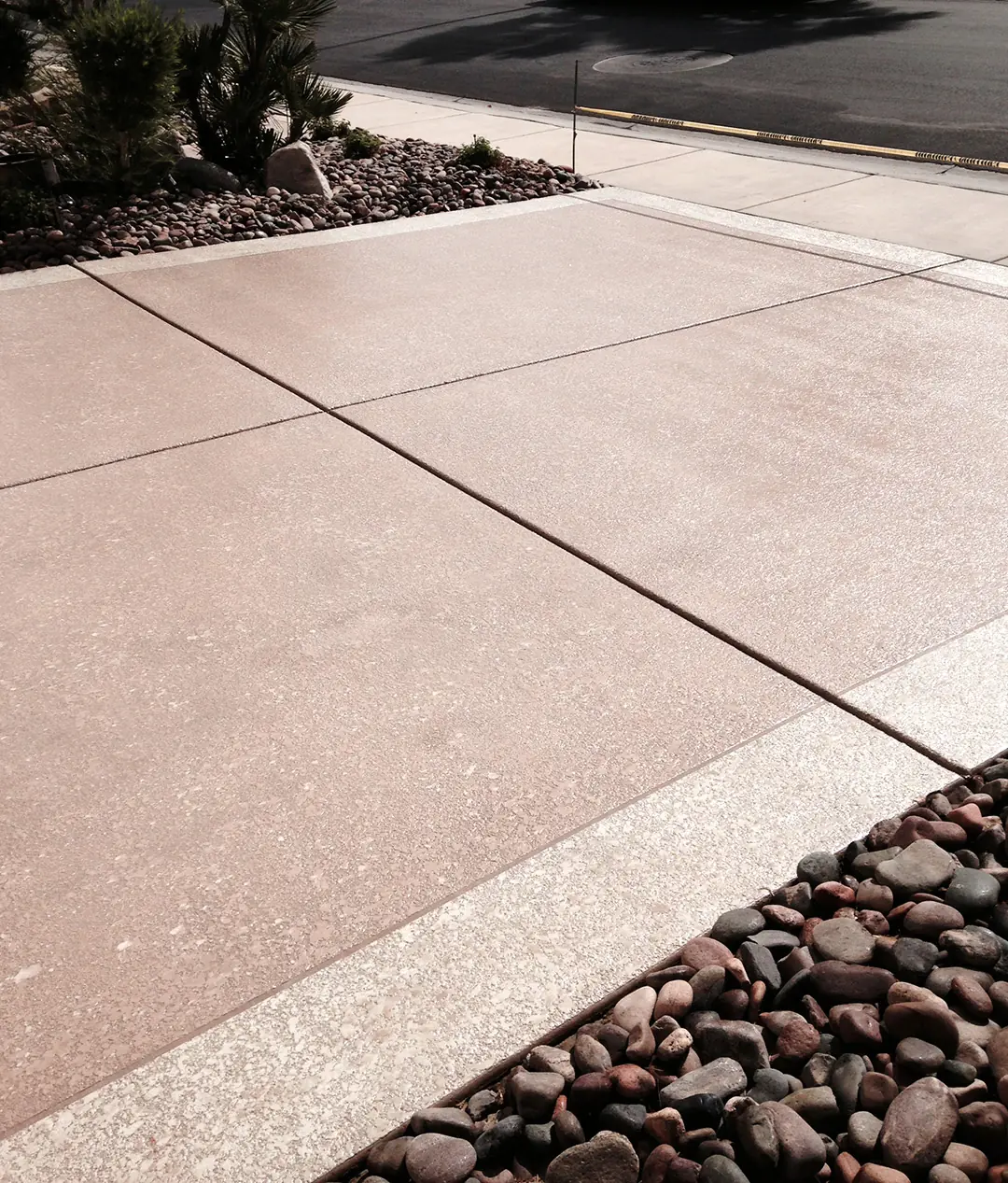 Tan textured deck edged with river rock landscaping