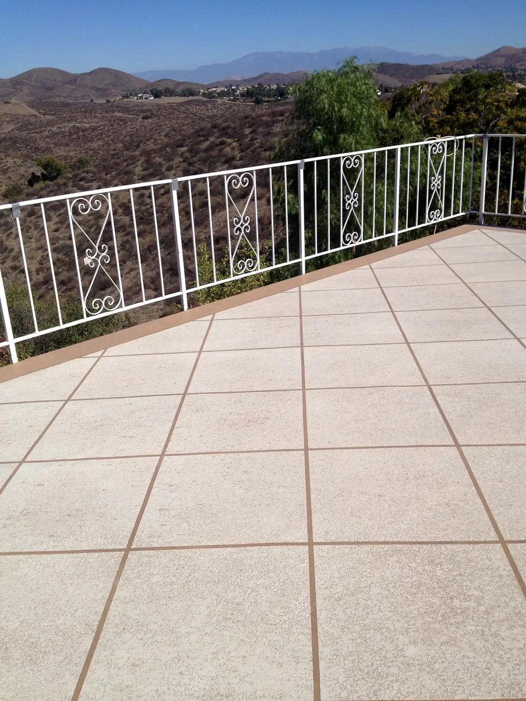 Tan textured patio deck behind a white railing with a valley view