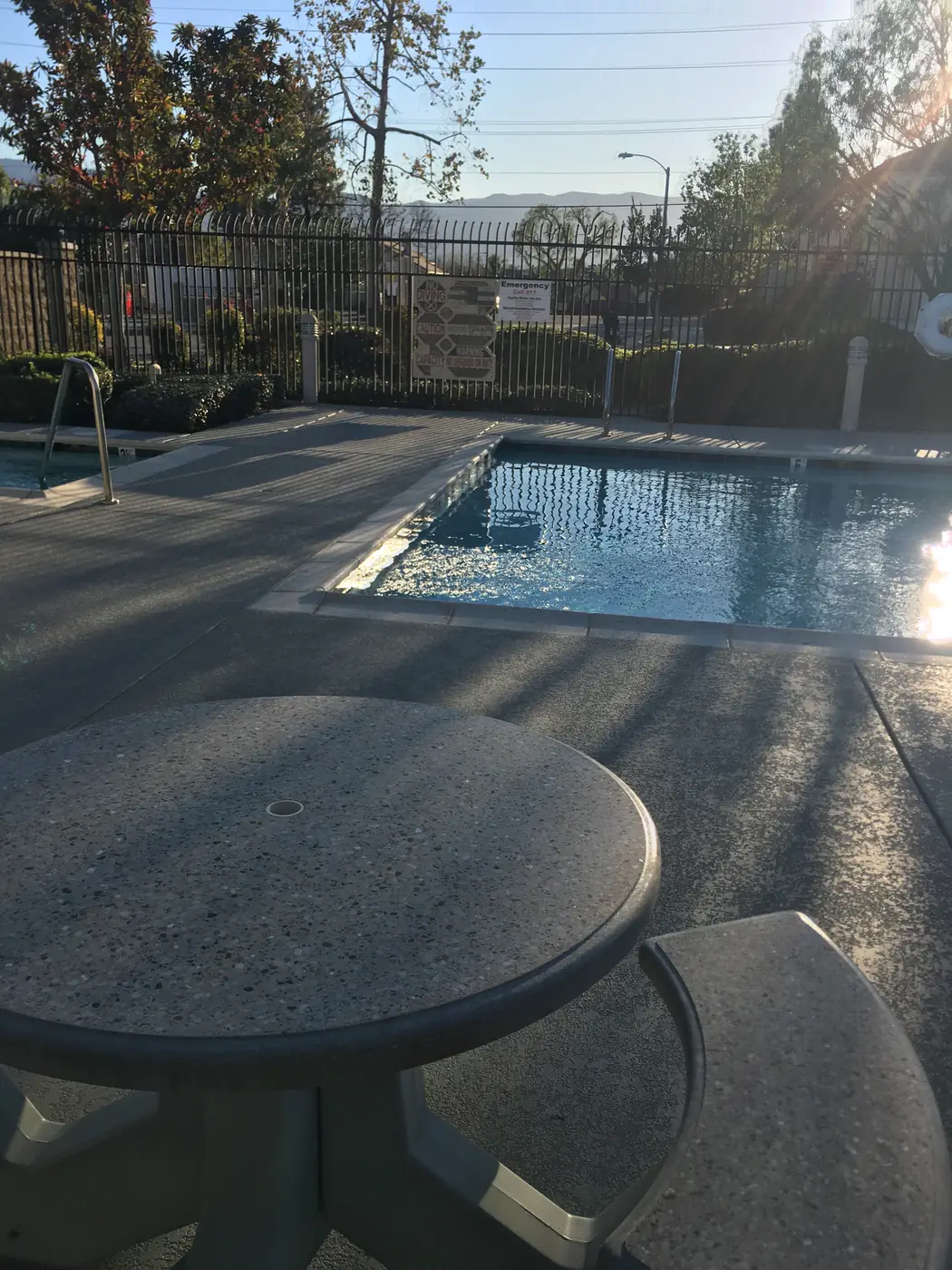 Gray textured deck and blue-gray border band running to a pool in low afternoon sun