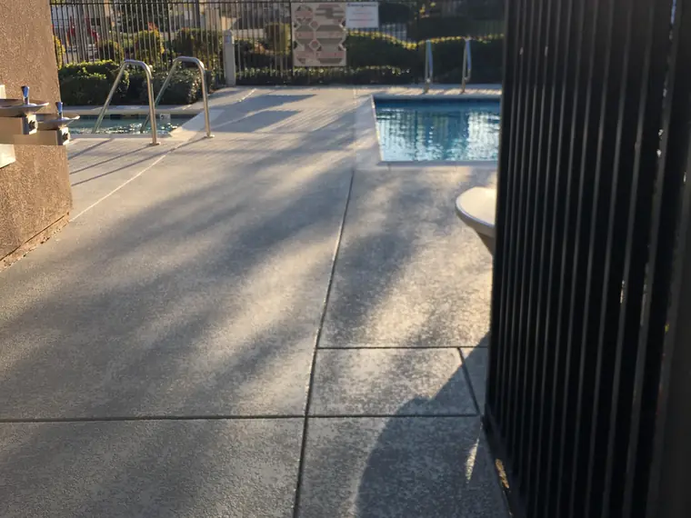 Blue-gray trim band along a gray textured deck beside a spa and pool