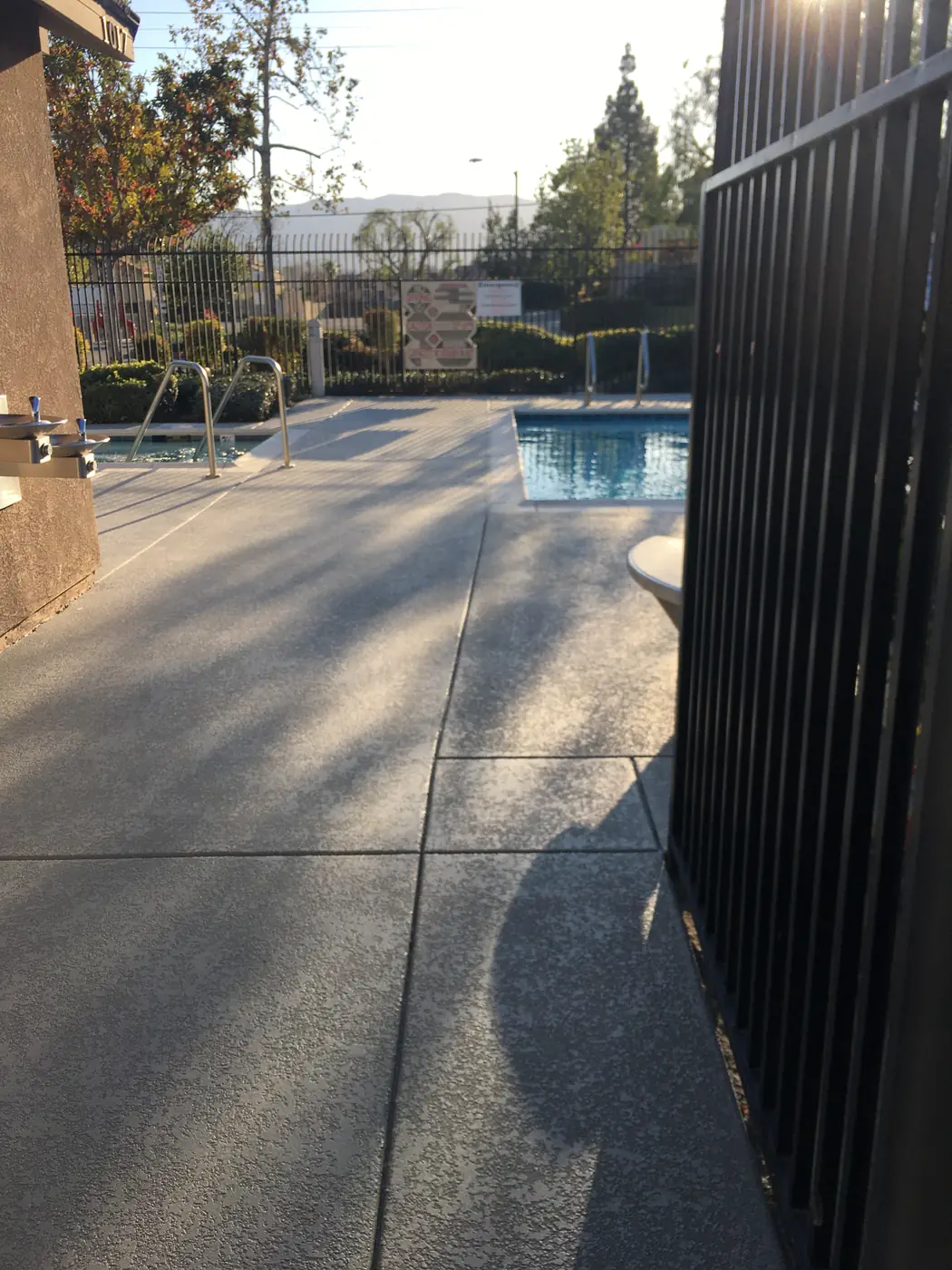Blue-gray trim band along a gray textured deck beside a spa and pool