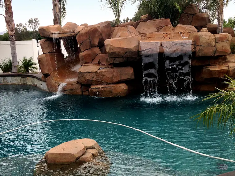 Restained faux rock waterfall spilling into a turquoise pool