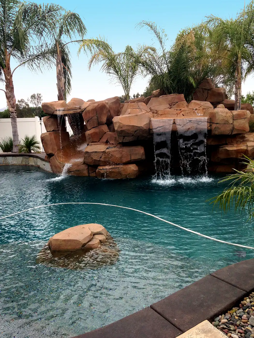 Restained faux rock waterfall spilling into a turquoise pool