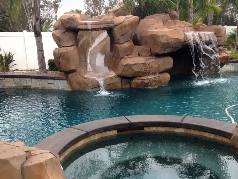 Restained rock grotto above a pool and spa