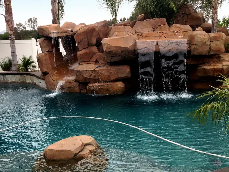 Rock waterfall feature and stained deck around a curved pool