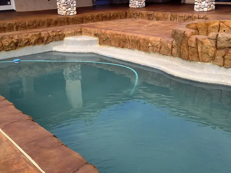 Stained pool deck and rock coping around a freeform pool