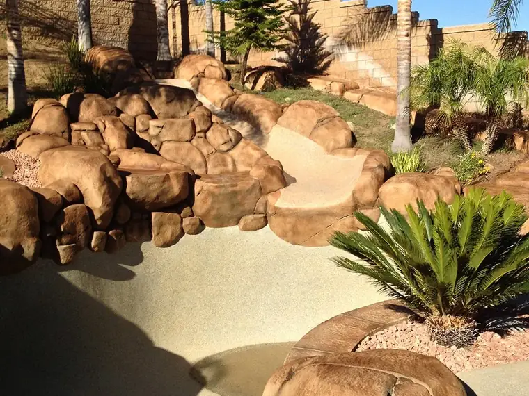 Restained boulder retaining wall with palms and desert planting