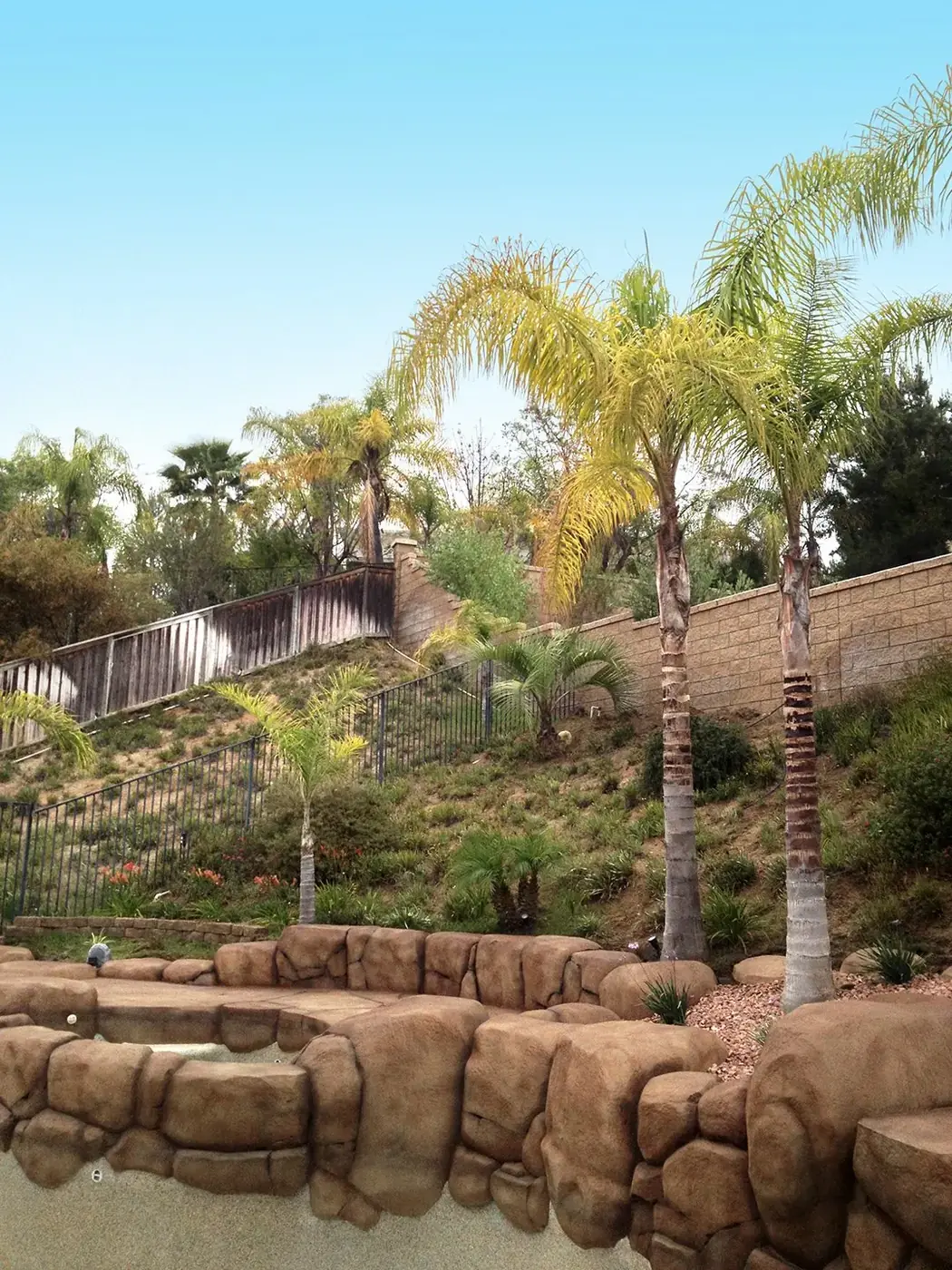 Restained rock retaining wall stepping up a planted hillside