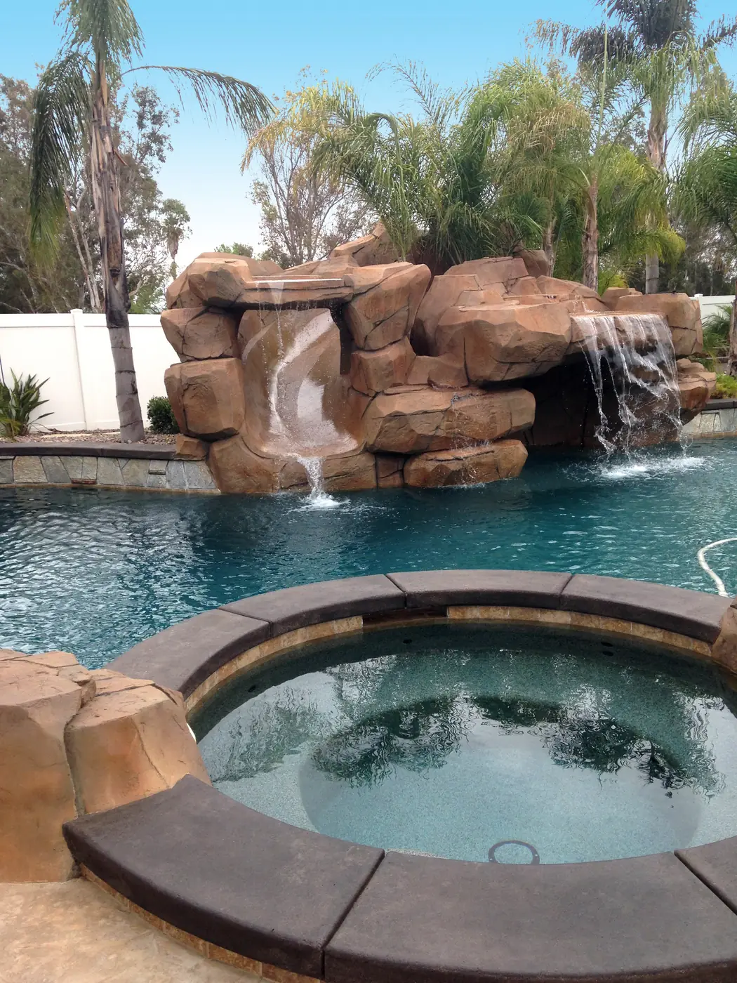Rock waterfall and raised spa above a pool after restaining