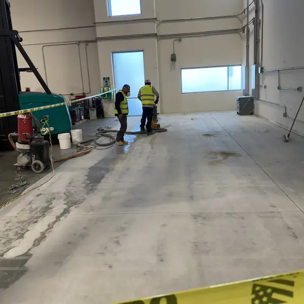 Crew and grinding equipment working across a warehouse slab during a coating removal