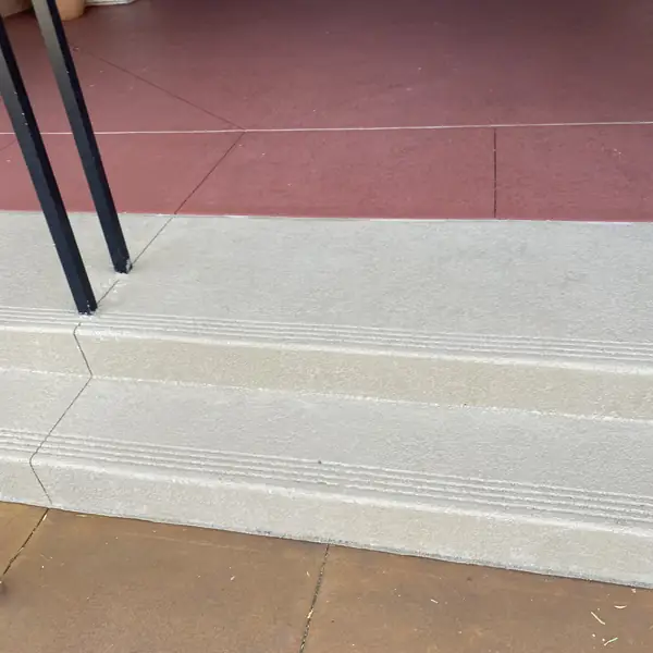 Resurfaced steps in cream with grooved treads and a red walkway beyond